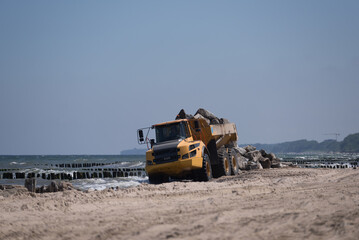 CONSTRUCTION DUMP TRUCK - A big vehicle carries boulders on the sea beach