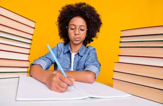 Portrait of attractive focused teen girl writing domestic work task subject isolated over bright yellow color background