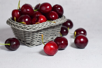 Fruit, close up, cherry season, inside a wicker basket and scattered, stone background.