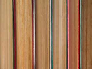 Abstract background of books standing vertically, a view of the book spines. Colorful hardcover books close-up.  A stack of hardcover books as a background, side view. Concept: education, training