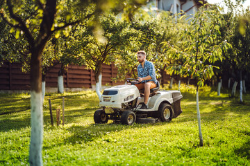 Industry details - portrait of gardener smiling and mowing lawn, cutting grass in garden