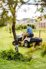 Professional lawn mower with worker cutting the grass in a garden