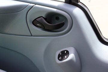 Driver door handle with windows controls and adjustments in modern cargo van. Window switches. Driver door trim cargo van.