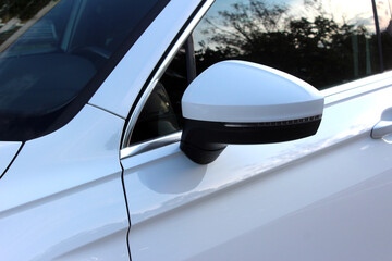 Fototapeta premium The rear view mirror on modern car. Rear-view mirror on a white car. Rearview mirror with reflection in it. Rear view mirror car on the road.