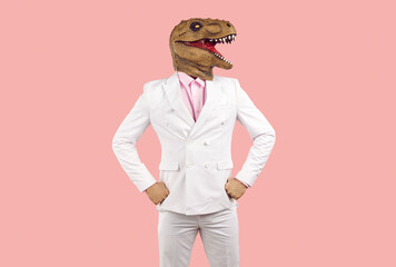 Portrait of a funny confident man wearing a stylish white suit and a goofy rubber T-rex dinosaur...