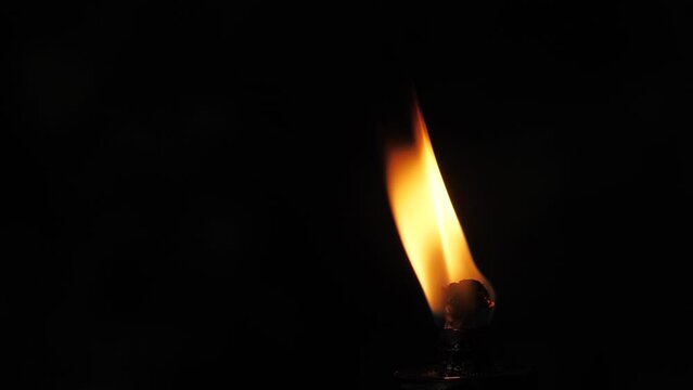 Fire flame from a torch on a black background. The flame of fire dances in the darkness. Soft cinematic picture. A strong flame that is blown across the screen. Soft selective focus.