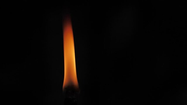Fire flame from a torch on a black background. The flame of fire dances in the darkness. Soft cinematic picture. Soft selective focus.