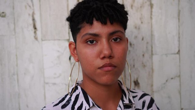 Serious non-binary person looking at the camera outdoors