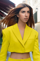 young redhead woman in yellow crop jacket on blurred street in Venice.