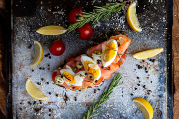 Fototapeta na wymiar Salted salmon open sandwich with eggs, tomatoes, olives, cream cheese, cucumber and garlick. Healthy seafood. Top view