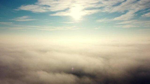 Aerial drone view flight over fog. Flight between white fluffy fog mist, clouds in blue sky and shining sun on sunny day. Natural abstract background. Cloudy weather. Atmosphere. Top view fog movement