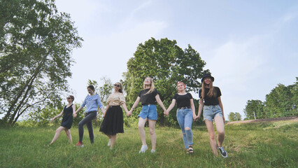 Obraz premium A group of girls are walking hand in hand outside the city.