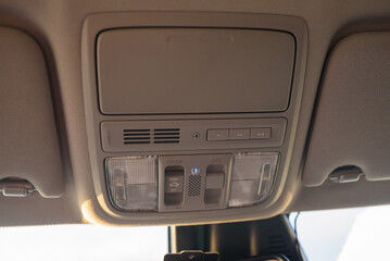 Buttons on the panel to open or close the hatch in the car. Сloseup of the hatch on the beige roof. Interior view of the car roof or ceiling light panel. Detail of modern car interior inside.