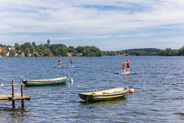 Fototapeta na wymiar People doing standup paddleboarding in the lake of Plon, Germany