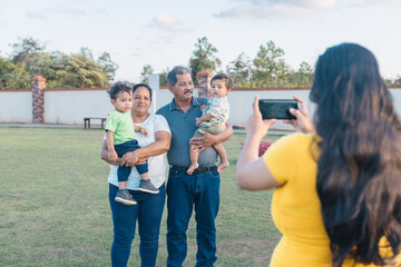 woman taking pictures of grandparents with grandchildren in the park
