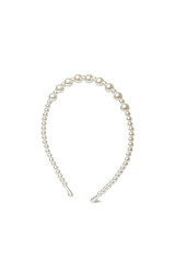 Close-up shot of a thin metal headband with shiny pearl beads. The elegant headband with pearl beads is isolated on a white background. Side view.