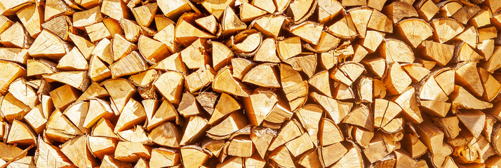 Textured firewood background of chopped wood for kindling and heating the house, a woodpile with stacked firewood. Concept of economic fuel crisis.