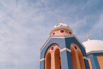 Beautiful church building decorated in bright colour and adorned with a cross. Dome church in Santorini with brightly decorated exterior