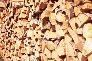 Textured firewood background of chopped wood for kindling and heating the house, a woodpile with stacked firewood. Concept of economic fuel crisis.