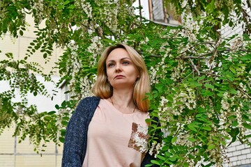 Beautiful middle-aged woman, in the spring on a background of blooming acacia.