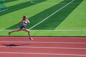 Young caucasian woman is engaged in jogging at the stadium outdoors.