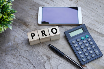 Word PRO on the wooden cubes with a calculator and smartphone on the wooden table 