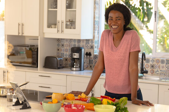 Portrait of cheerful young african american preparing food in kitchen at home
