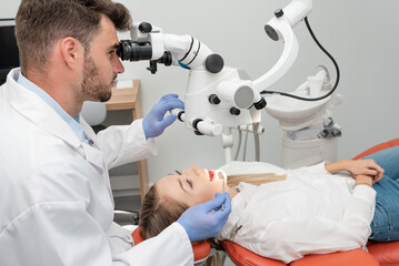 Naklejka na ściany i meble Male dentist working with dental microscope