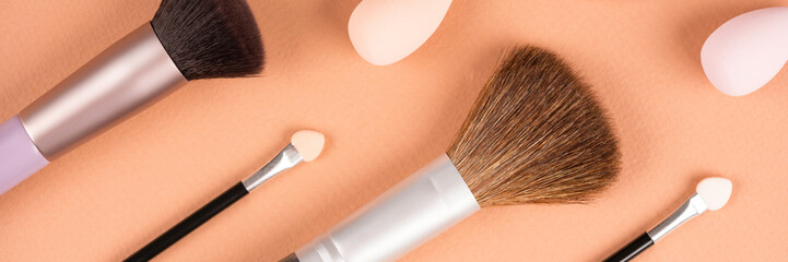 Makeup and beauty concept. Different makeup brushes, sponges and applicators over pastel beige background. Flat lay style banner