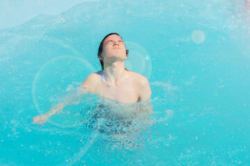 a wet guy jumps out of the water of the pool with closed gases in the sun, a man bathes me in the pool on a summer day,private recreation