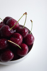 Red juicy sweet cherry in drops of water close-up on a light background