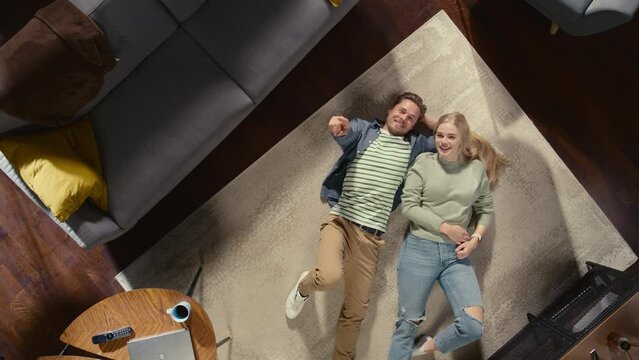 Top View Apartment: Young Couple in Love Lying on the Floor and Talking, Sharing their Dreams, Aspirations and Hopes. Girlfriend and Boyfriend Planning Brighter Future Together in a Cozy Living Room
