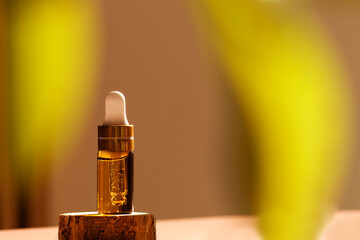 Cosmetic amber glass dropper bottle on wooden podium with oil, serum or fruit peeling in the...