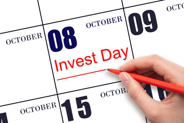 Hand drawing red line and writing the text Invest Day on calendar date October 8. Business and financial concept.