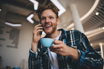 Guy drink tea and talk on smartphone in office