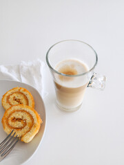 Latte macchiato coffee and swiss roll, roll cake over white background