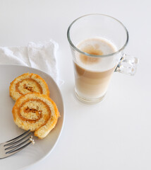 Latte macchiato coffee and swiss roll, roll cake over white background