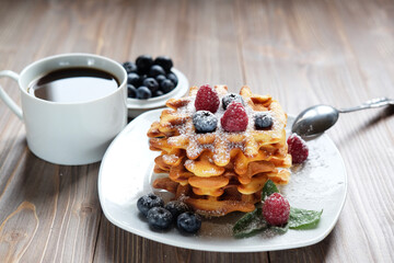 Belgian waffles with fresh berries over wooden background