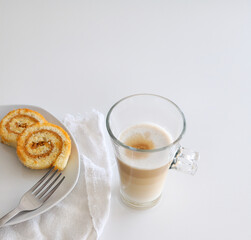 Latte macchiato coffee and swiss roll, roll cake over white background