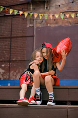 Cute girlfriend girls dressed in hip hop rock hipster style are sitting on the steps of the city...