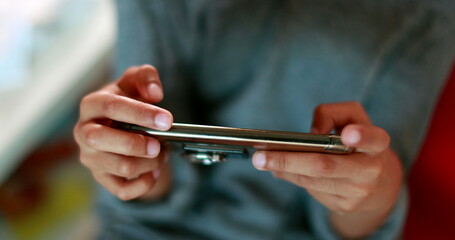 Child holding smartphone playing video-game. Mixed race boy looking at cellphone screen