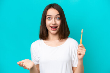 Young Ukrainian woman brushing teeth isolated on blue background with shocked facial expression