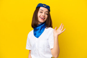 Airplane stewardess Ukrainian woman isolated on yellow background saluting with hand with happy expression