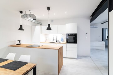 Modern kitchen with a dining area and a counter. White and wooden furniture