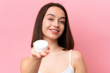 Young Ukrainian woman isolated on pink background with moisturizer and offering it