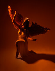Full length portrait of beautiful red head woman wearing long flowing fantasy toga gown with golden halo crown and angel wings,  dancing standing pose  on a dark moody background with glowin