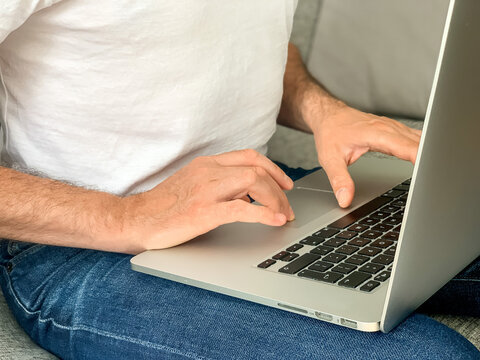 Man sitting on sofa before going to office using laptop making report checking business index home. IT specialist, code developer, python, coder