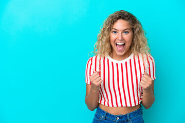 Girl with curly hair isolated on blue background celebrating a victory in winner position