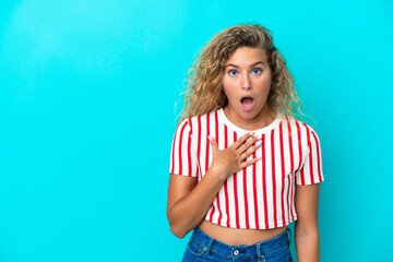 Girl with curly hair isolated on blue background surprised and shocked while looking right
