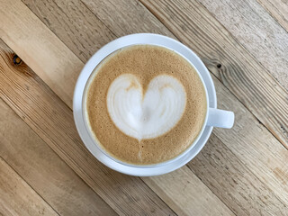 A cup of coffee latte On a wooden table. A mug of flat white coffee on a wooden background. Coffee art. Heart flower shape latte art. Copy space